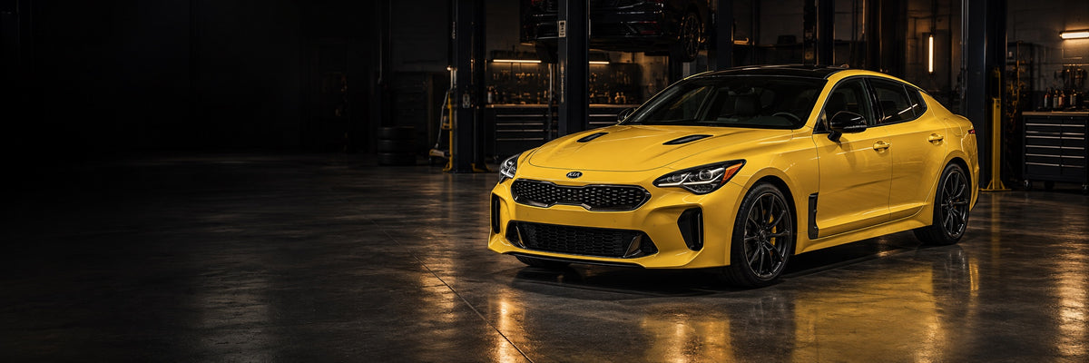 Yellow Kia Stinger in a dark automotive workshop